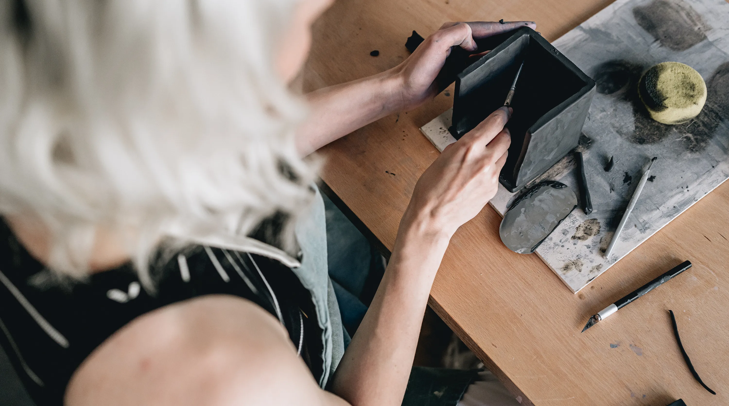 Dokumentarisches Foto einer Keramikerin, die einen Würfel aus Ton formt